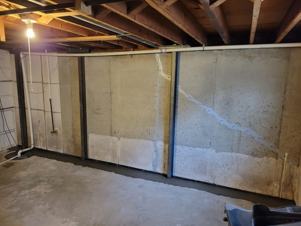 Finished basement wall with steel restraints and sealed cracks