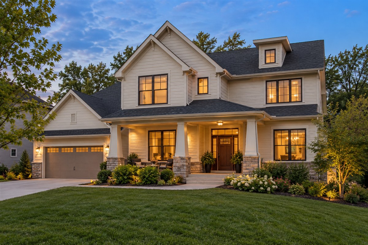 Cream two-story suburban home with a front porch and stone accents at dusk