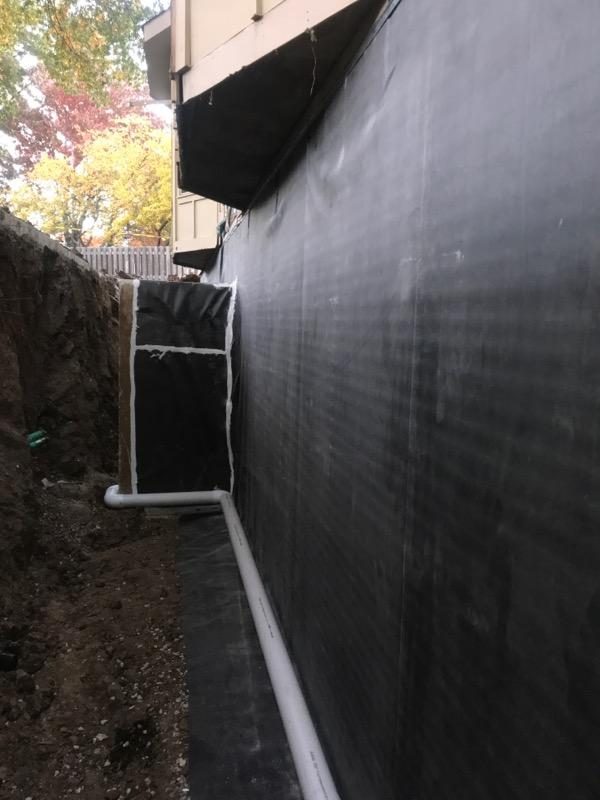 Waterproofing membrane and drain pipe along the outside of a foundation wall in an open trench