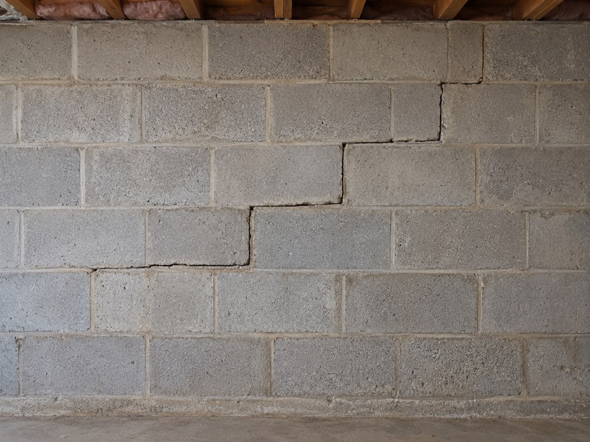 Stair-step crack running diagonally through the mortar joints of a block basement wall