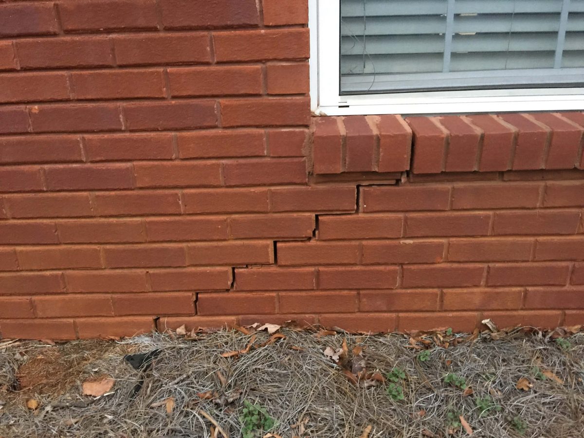 Stair-step crack running through the brick below a window