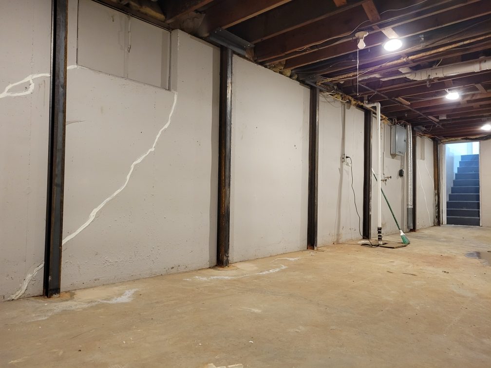 Steel wall restraints bolted to a cracked poured concrete basement wall